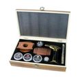 A premium smoking accessories gift set presented in an open wooden box with a black foam-lined interior. The set includes a wooden cigar cutter, a wooden cigar holder, three small tin cans of rolled chips, a glass pipe, a brass and black torch lighter, and a glass rolling pin, all neatly arranged on a white background.