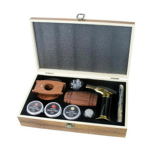 A premium smoking accessories gift set presented in an open wooden box with a black foam-lined interior. The set includes a wooden cigar cutter, a wooden cigar holder, three small tin cans of rolled chips, a glass pipe, a brass and black torch lighter, and a glass rolling pin, all neatly arranged on a white background.