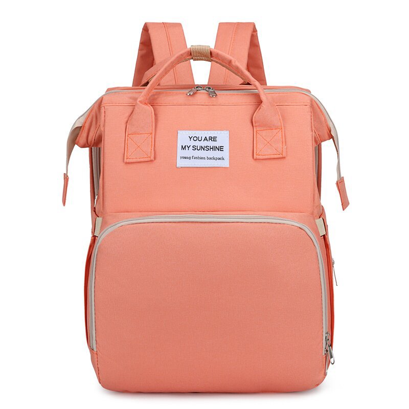 Peach-colored backpack with a motivational quote tag on a white background