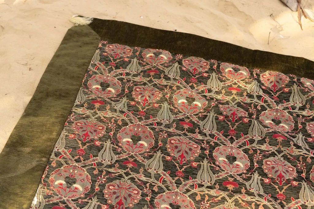 Close-up of pink flowers and pale leafy outlines beside an olive rug border