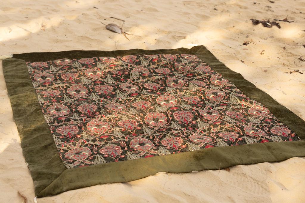 Square olive and pink floral Turkish rug shown in a beach styling scene
