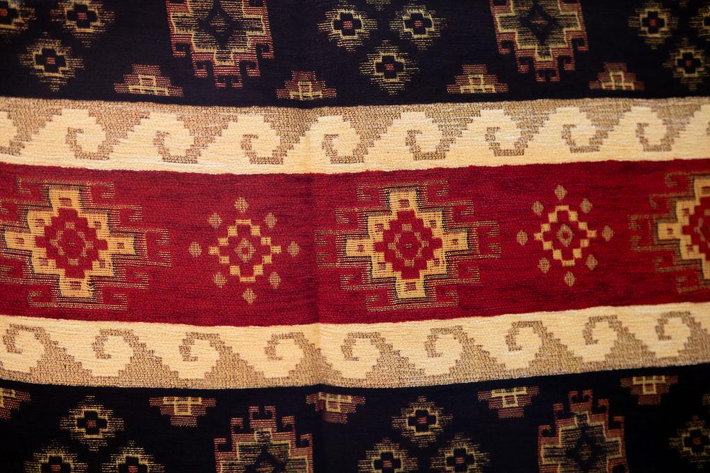 Close-up of red geometric band between cream scrolling stripes and dark navy motifs