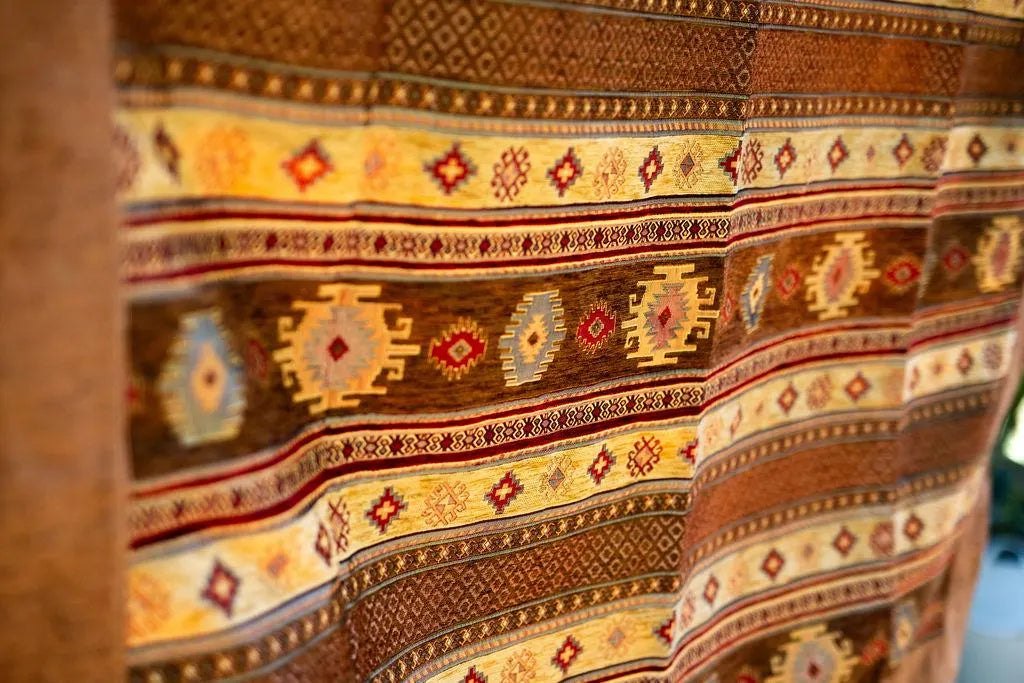Square brown Turkish rug with yellow geometric bands, wide brown border and pale corner tassel
