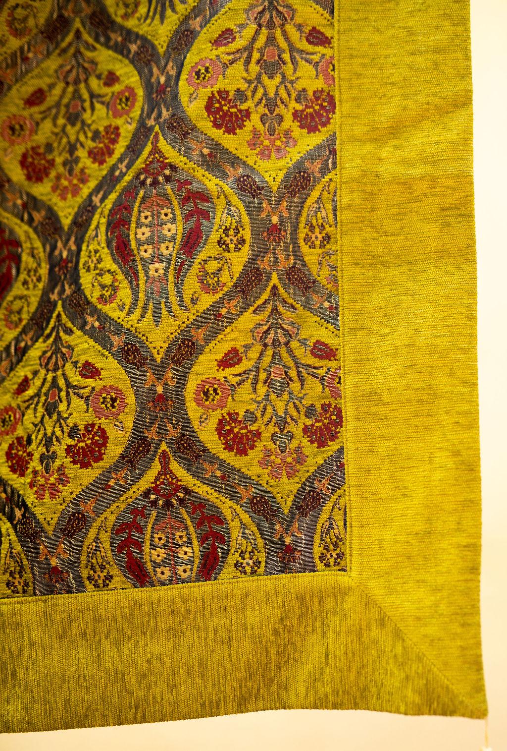 Corner detail of yellow Turkish rug showing floral motifs and broad yellow border