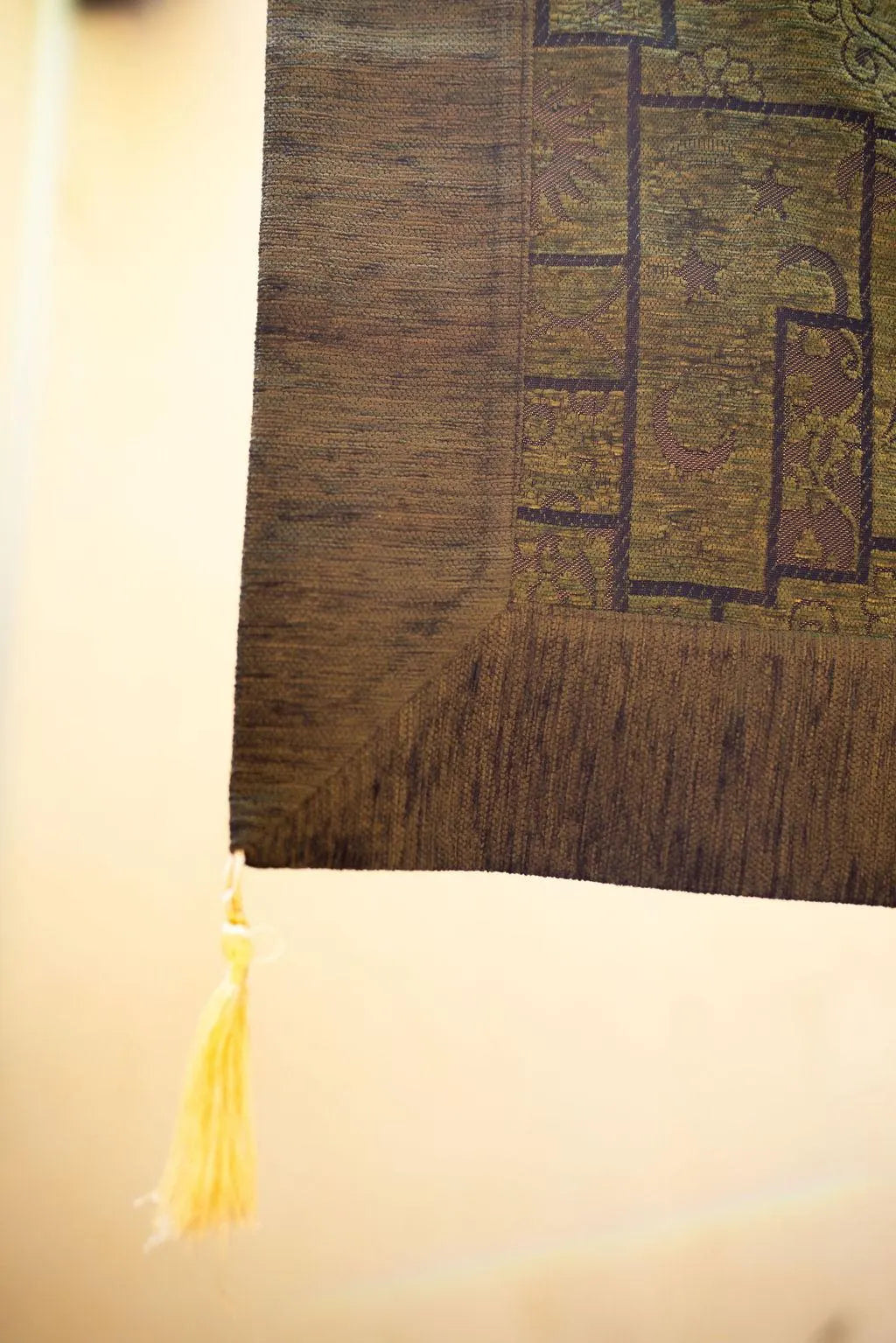 Corner detail of olive Turkish rug showing its plain border and tassel