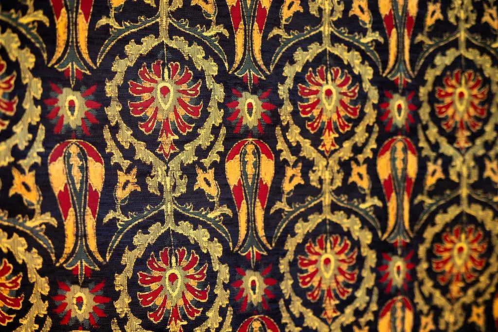 Close-up of red flowers, gold-tone leafy scrolls and tulip-like motifs on a dark navy rug