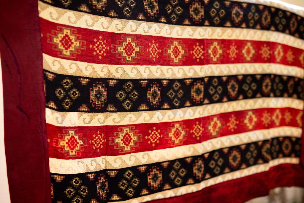 Detail of stepped diamond motifs across red and navy rug stripes