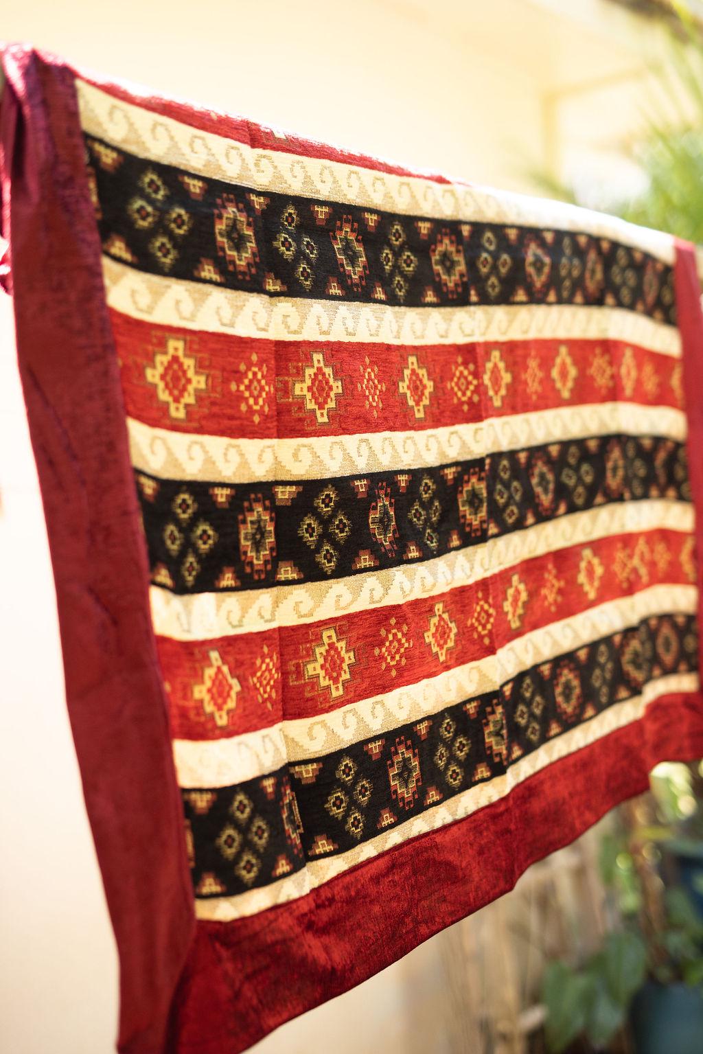 Square Turkish rug with red and navy geometric bands, cream stripes and a plain red border