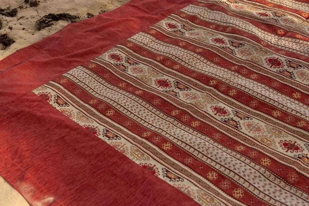 Close-up of red rug border and cream bands with repeating geometric motifs
