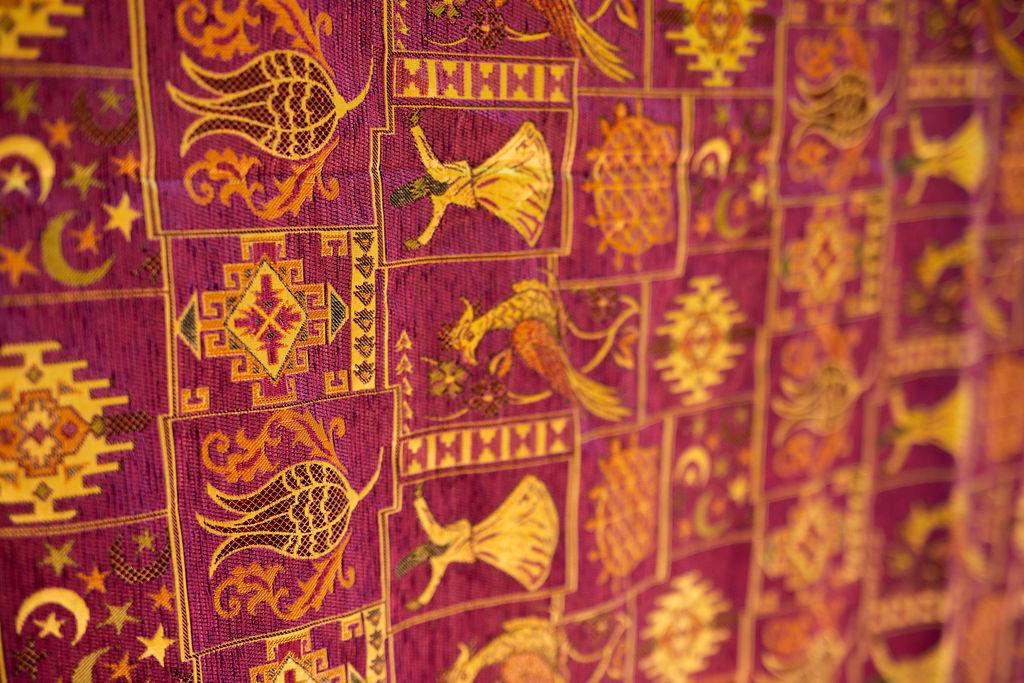 Corner of burgundy Turkish rug showing plain border and red tassel